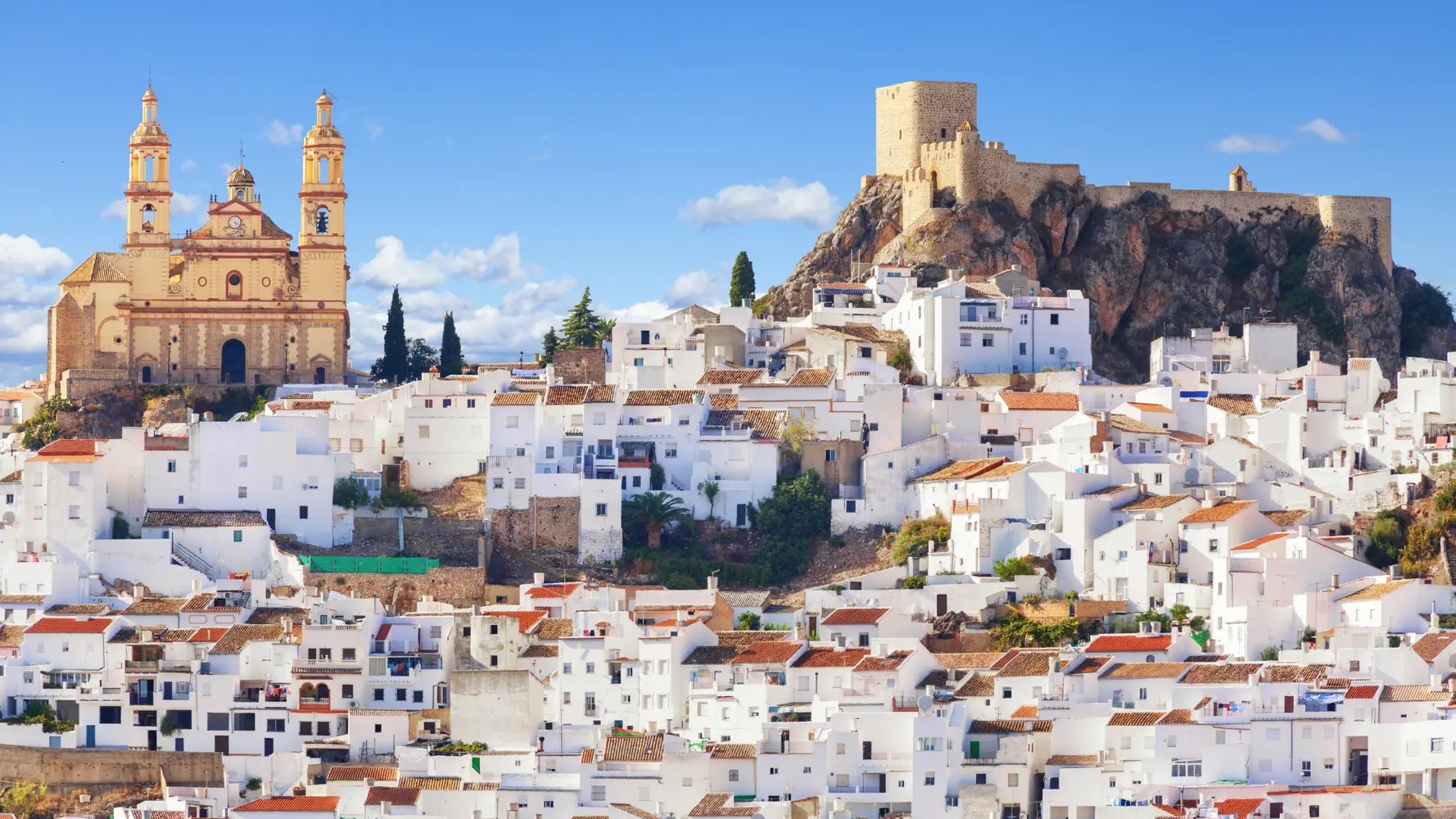 Vue d’un village blanc d’Andalousie avec maisons blanches perchées sur les collines sous le soleil.